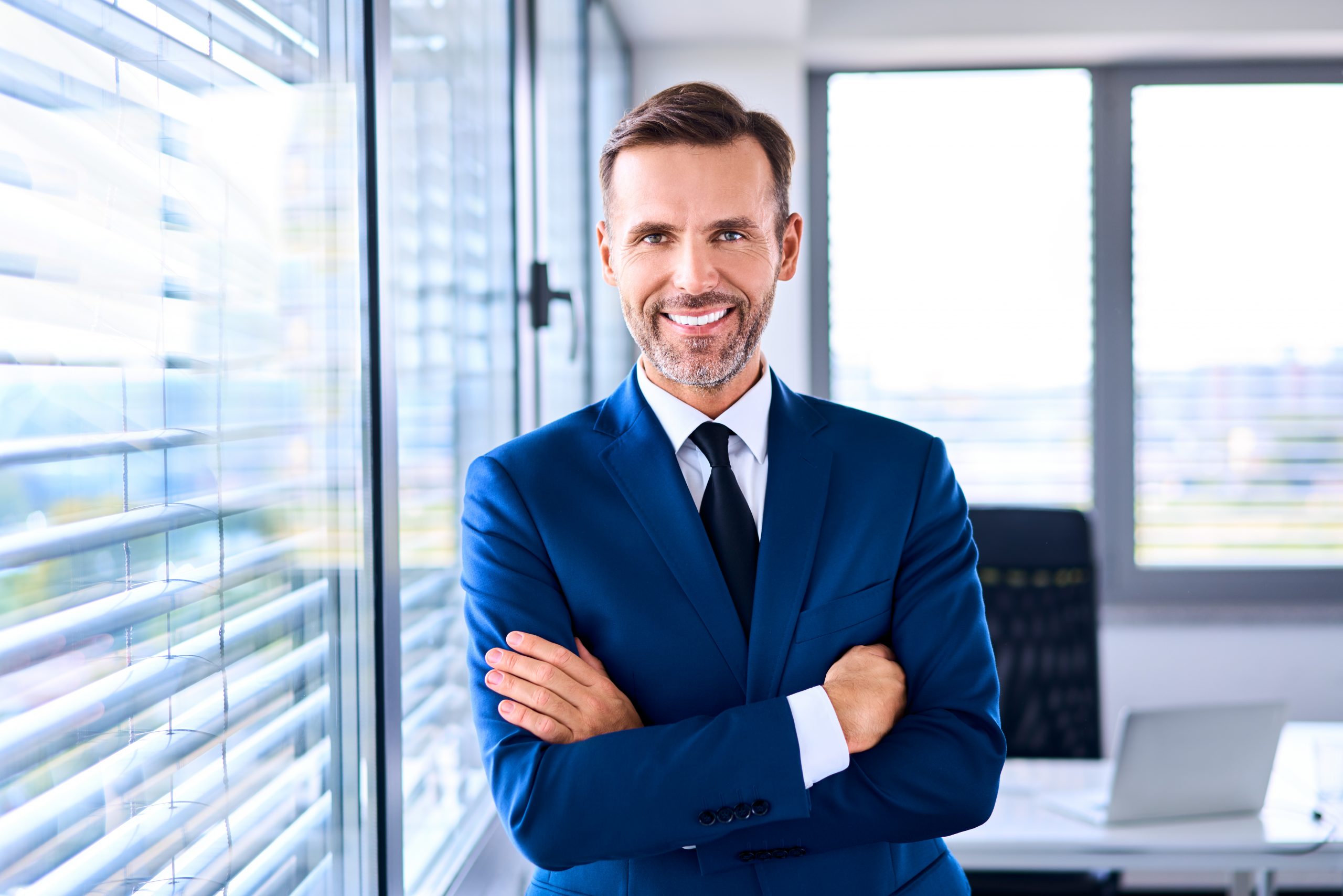 Smiling Male Growth Coach in Blue Blazer in Modern Office Setting